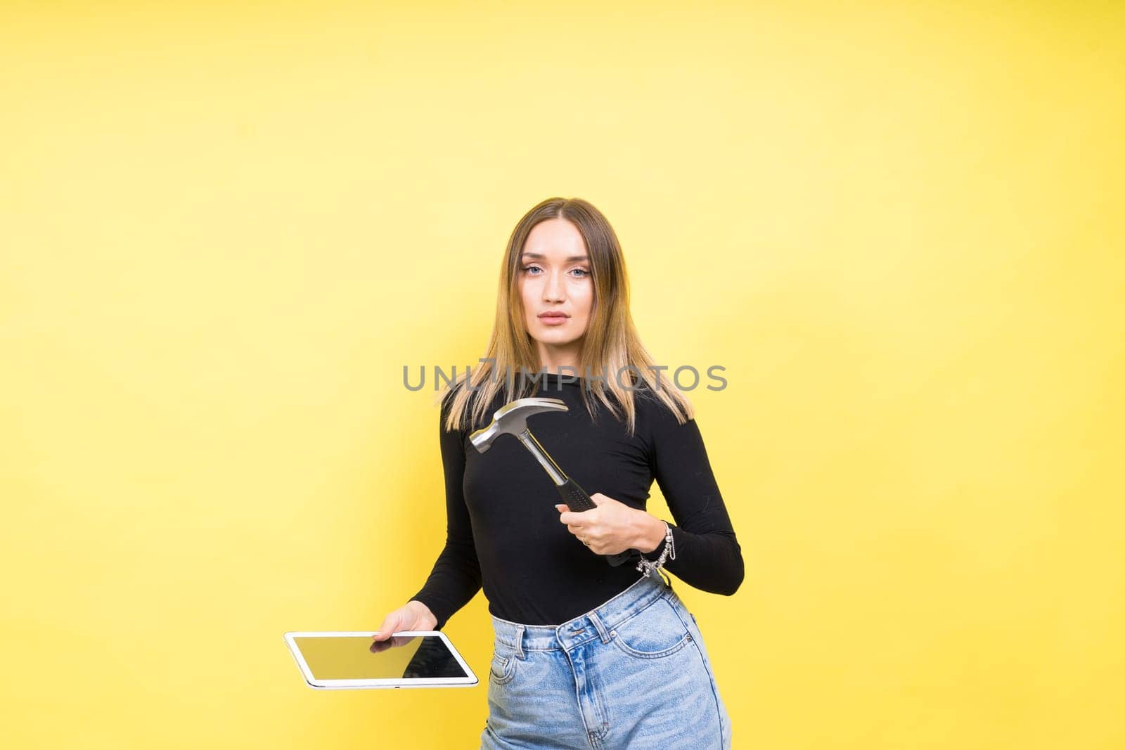 Attractive blond hair woman wearing business suit in front of computer holding a hammer