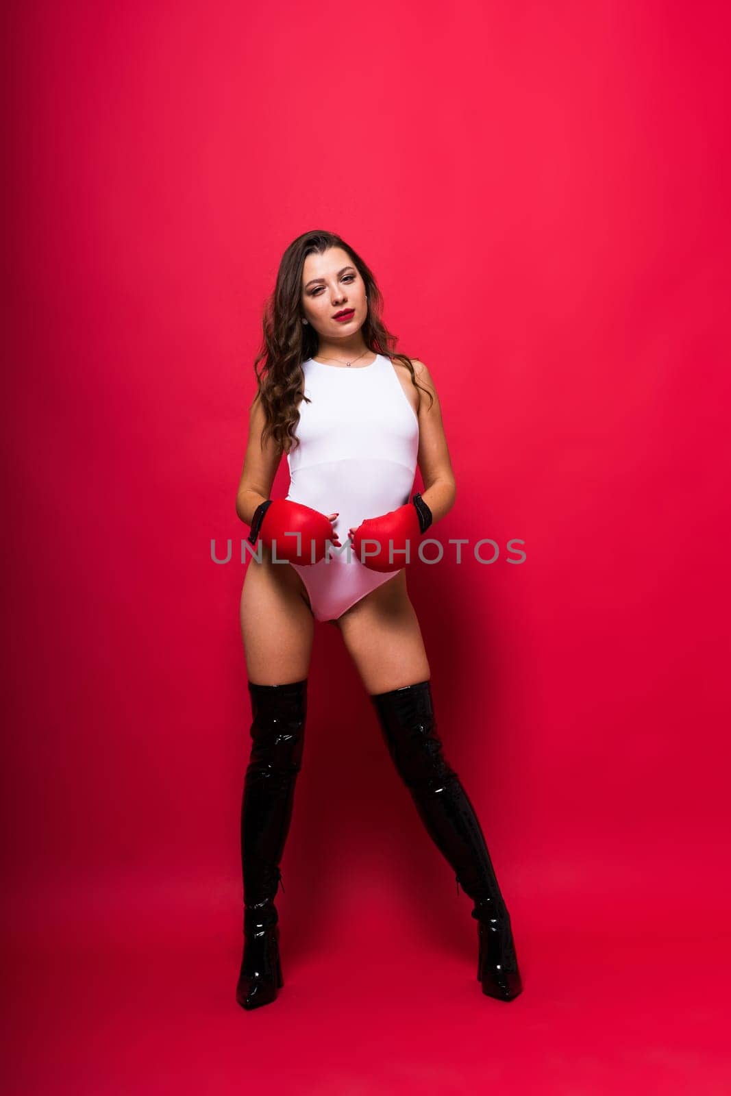 Seductive young female in violet bodysuit on dark and red background by Zelenin