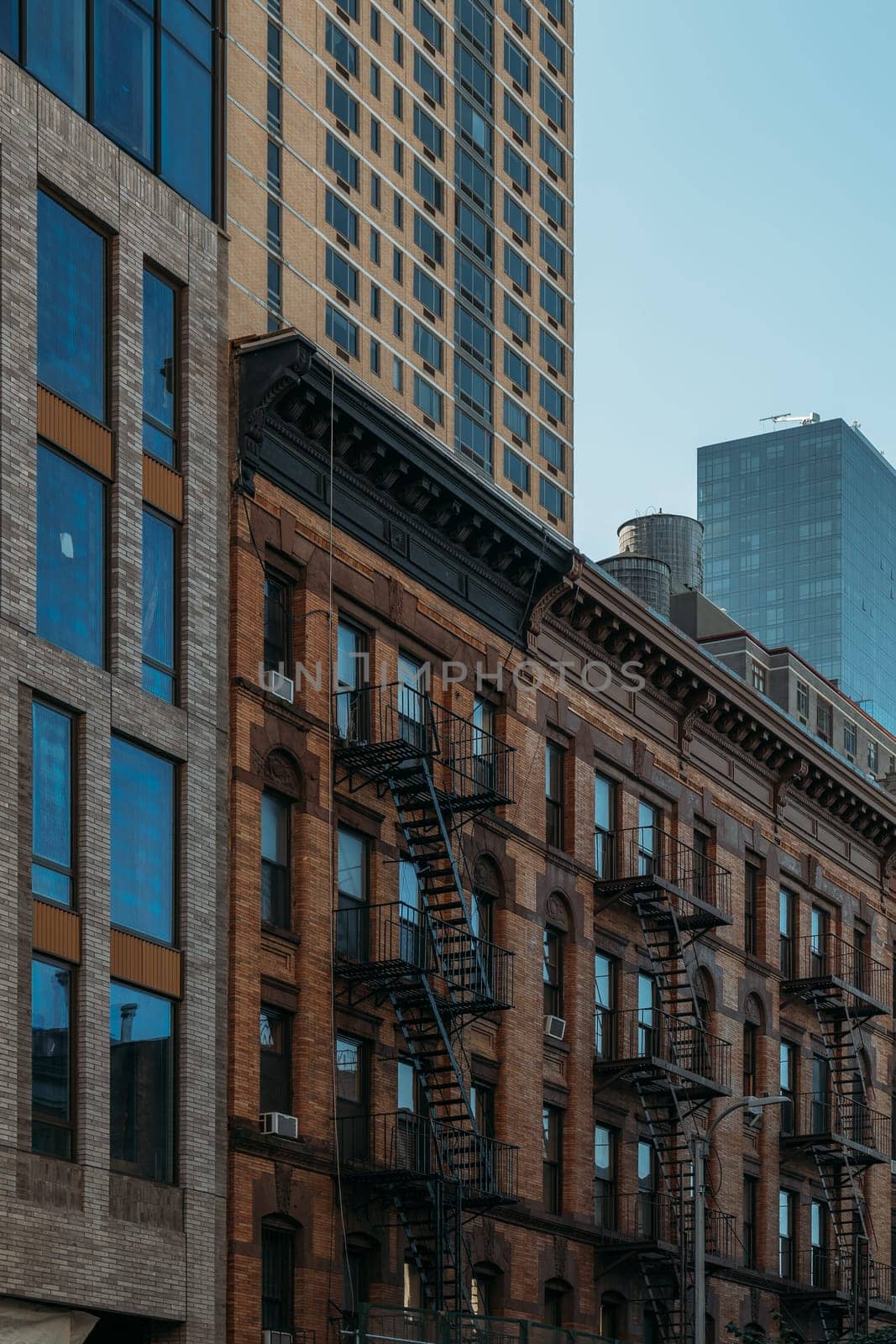 A blend of historic New York City buildings featuring classic fire escapes contrasting with a modern high-rise in the background.