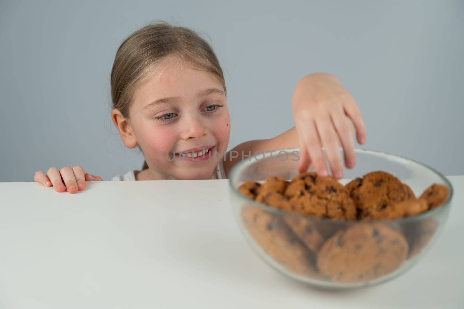 Little girl steals cookies from the table