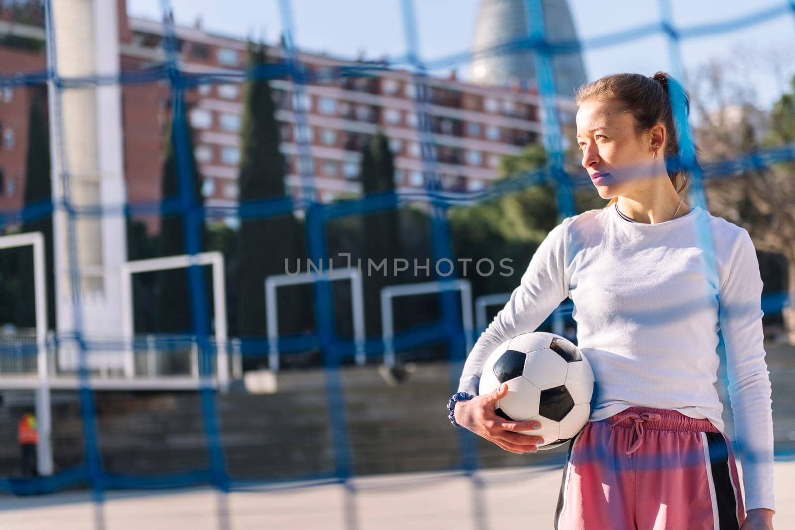 caucasian female football player holding a soccer ball on an urban court, concept of sport and active lifestyle, copy space for text