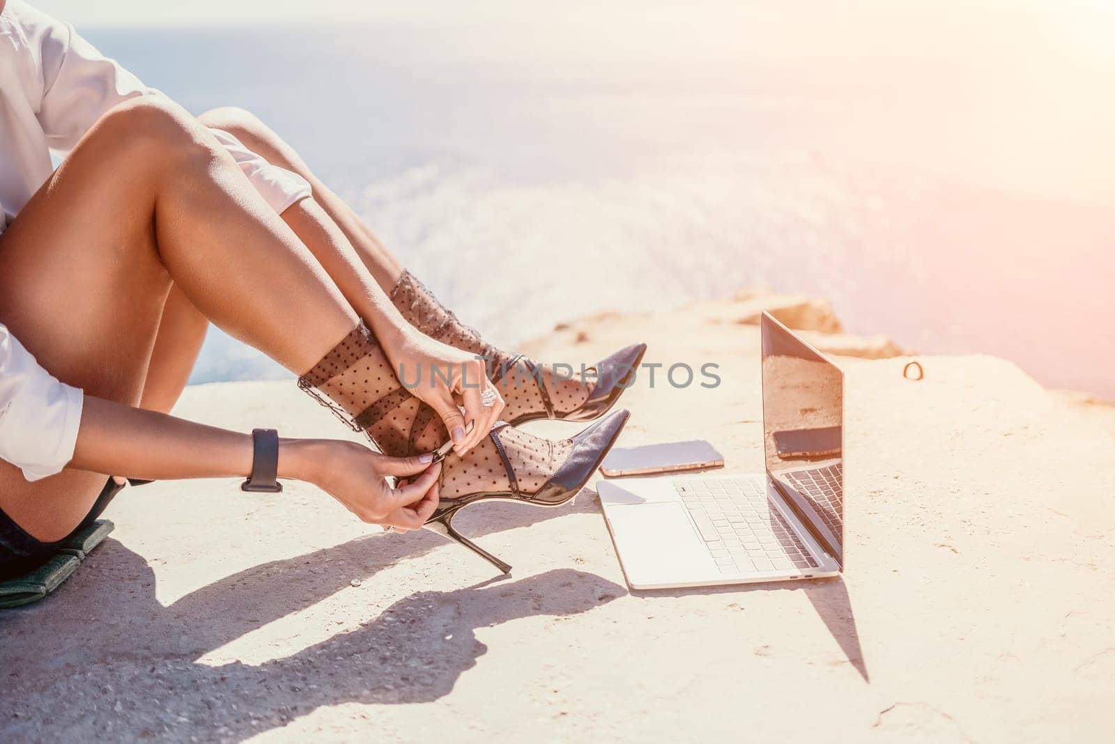 Woman sea laptop. Business woman in yellow hat freelancer with laptop working over blue sea beach. Girl relieves stress from work. Freelance, digital nomad, travel and holidays concept by panophotograph