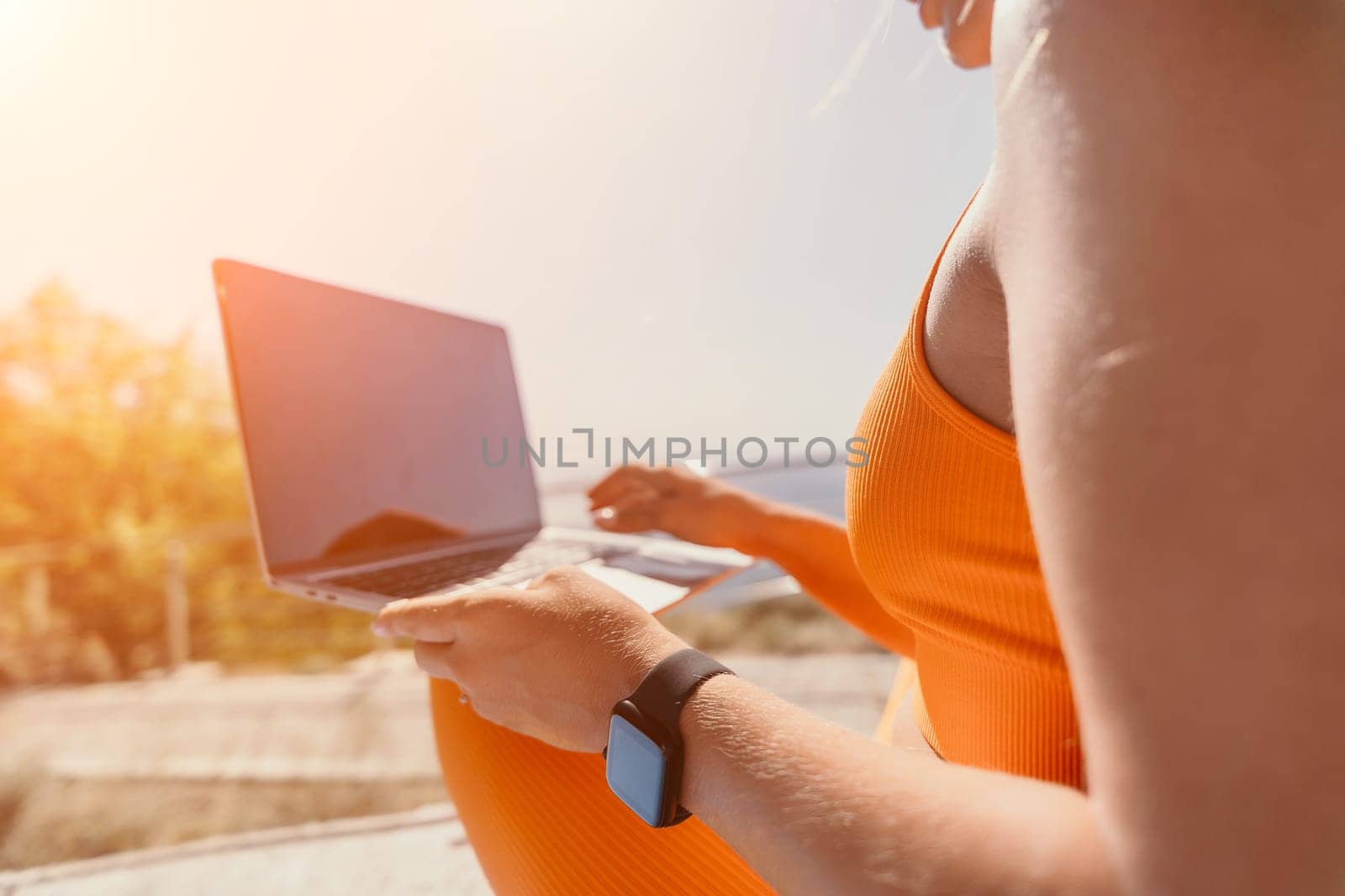 Digital nomad, Business woman working on laptop by the sea. Pretty lady typing on computer by the sea at sunset, makes a business transaction online from a distance. Freelance, remote work on vacation