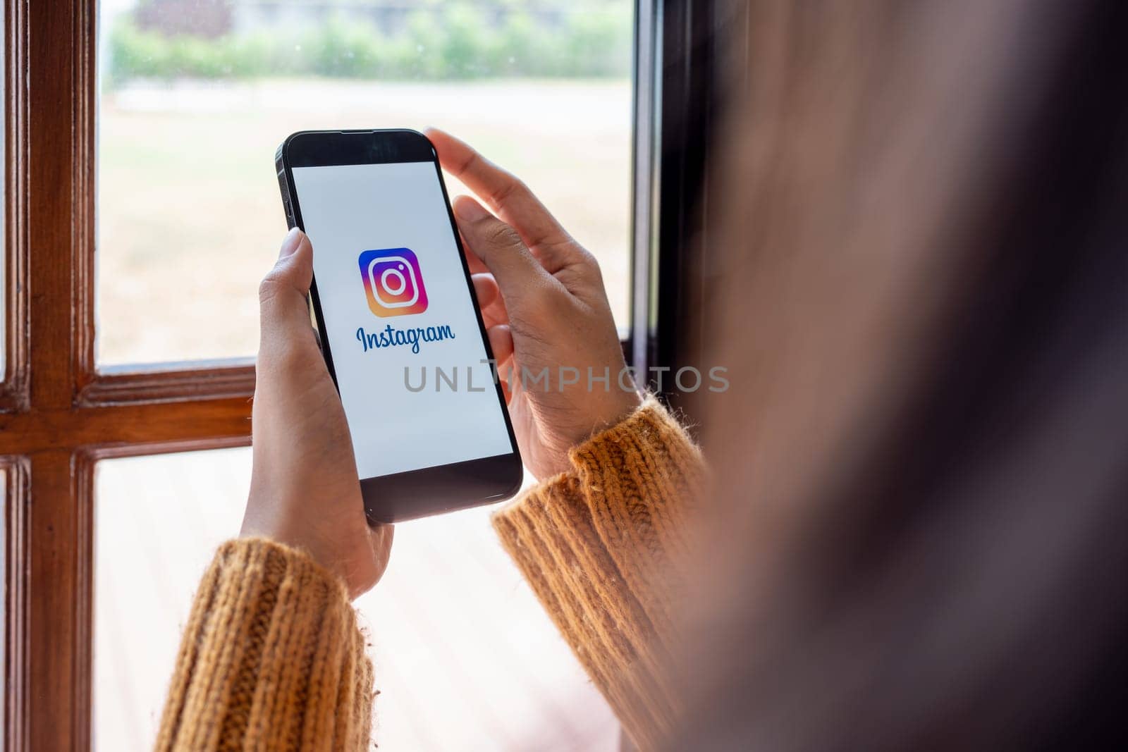 CHIANG MAI, THAILAND - April 30, 2023: A woman holds a smartphone mobile with an Instagram application on the screen is a sharing photo and story videos on the application