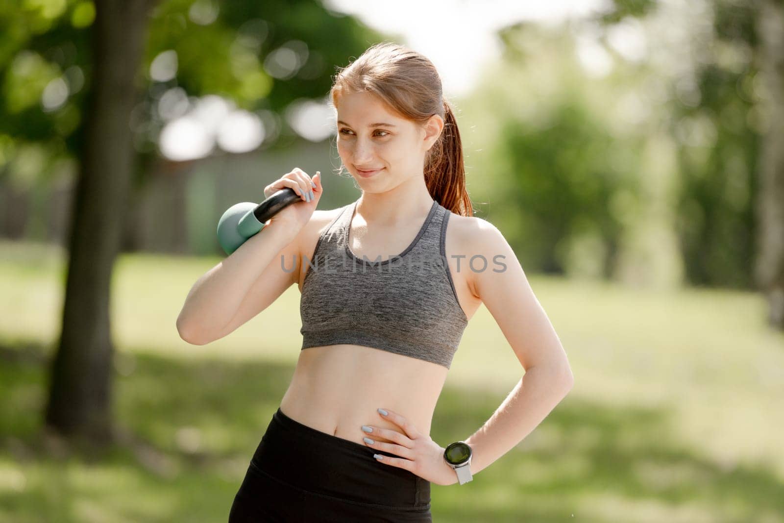 Girl Does Kettlebell Exercises Outdoors In Summer
