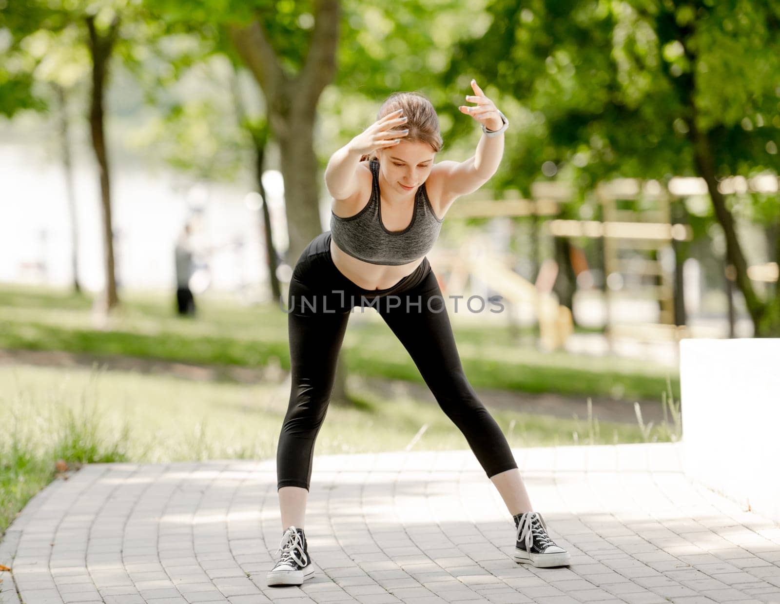 Sporty Teenage Girl Does Bends In Park During Summer