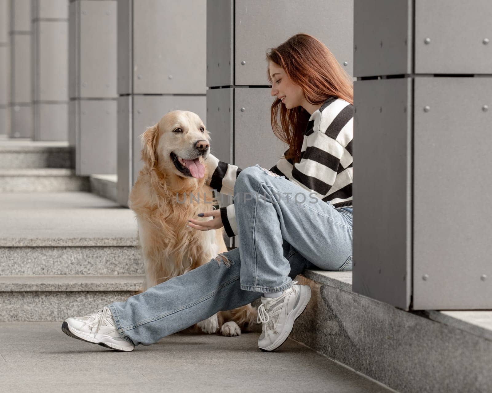 Teen Girl With Golden Retriever Sits In City During Spring