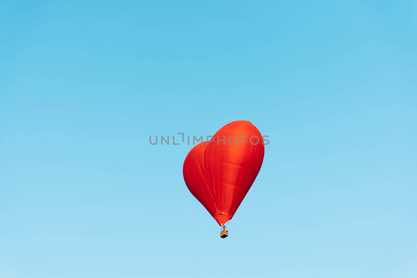 red heart shaped balloon soaring through the clear blue sky on a sunny day by Vichizh