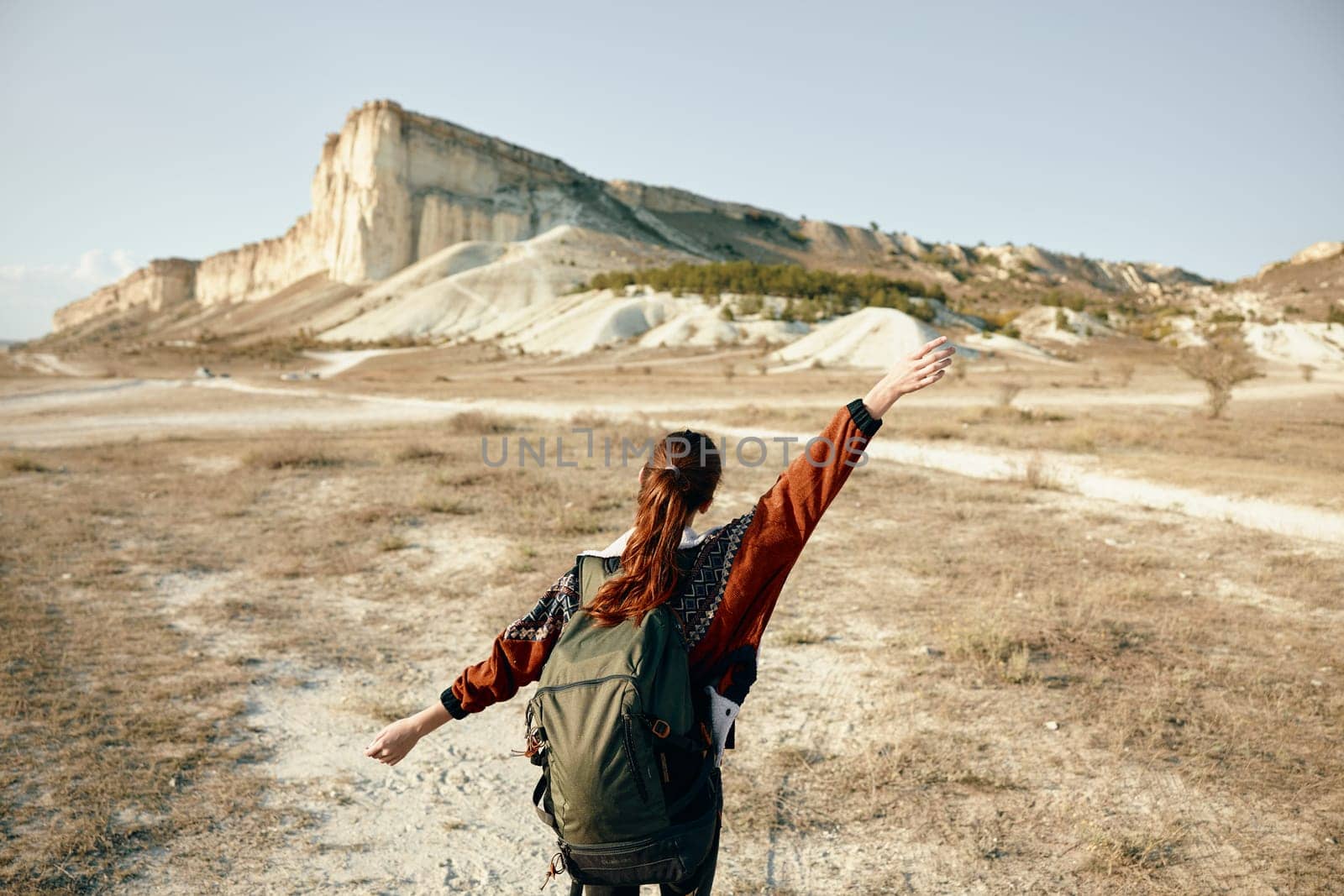 freedom in nature woman with backpack standing in field with arms outstretched by Vichizh