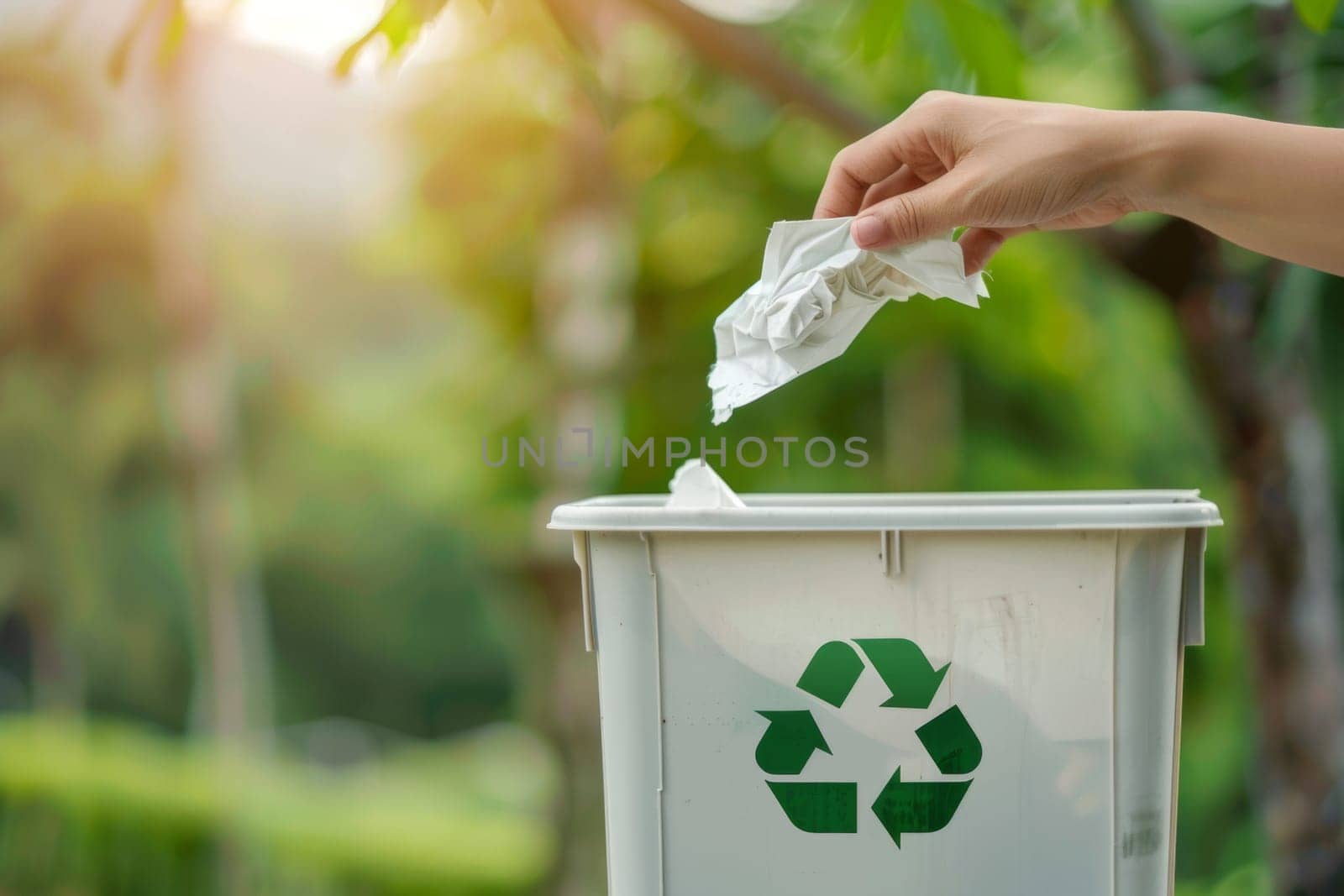 Hand putting waste paper into a trash bin with recycling icon. Save the planet concept.