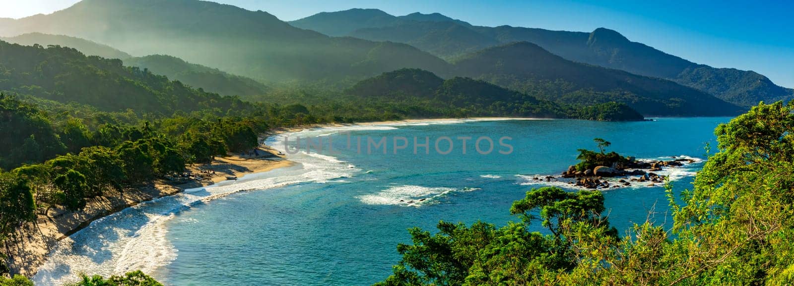 Panoramic image of Castelhanos beach between the sea, mountains and forests of the island of Ilhabela on the coast of Sao Paulo