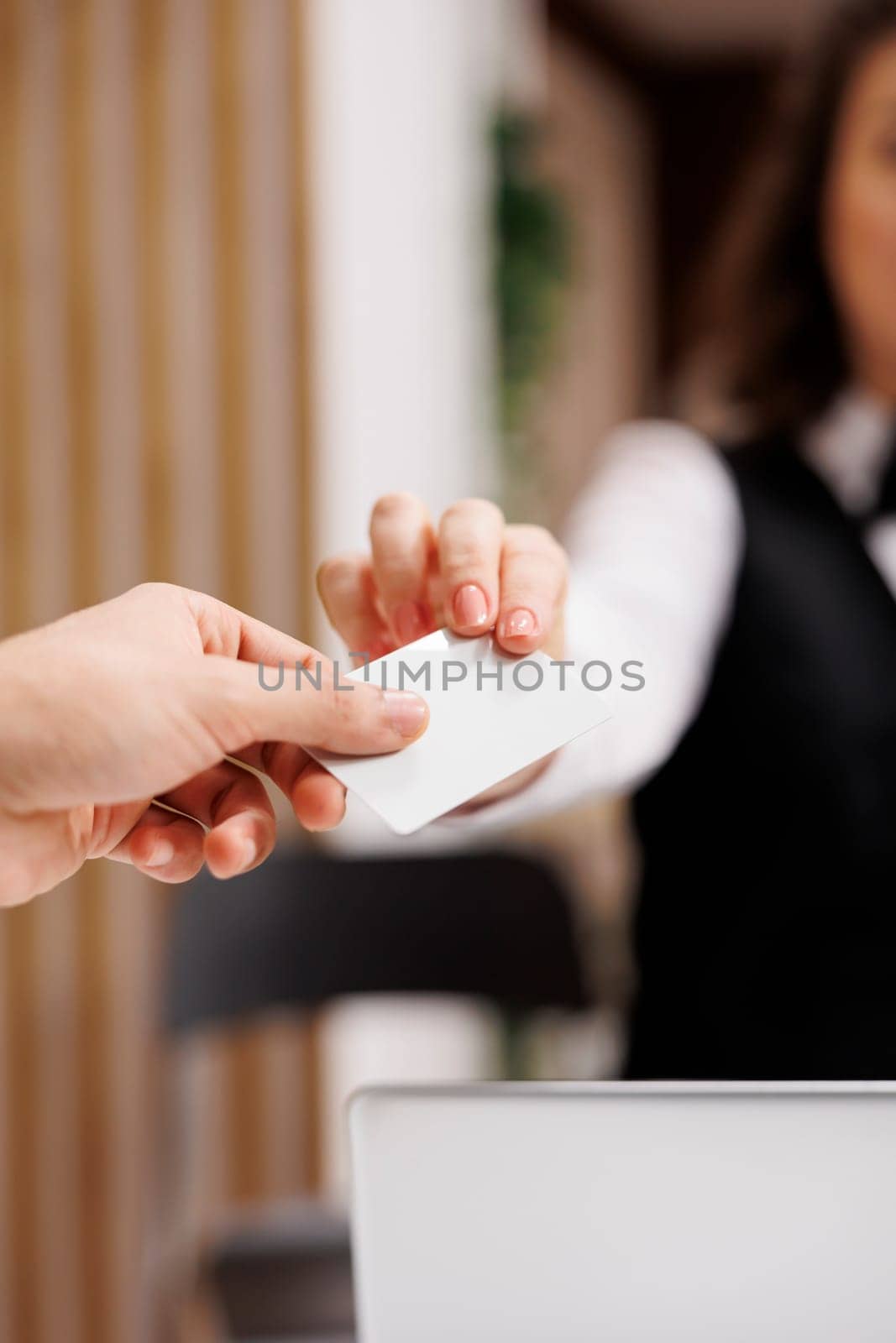 Businessman taking room key card in lobby, gaining access to accommodation before attending conferences on business trip. Young adult doing check in at hotel front desk. Close up.