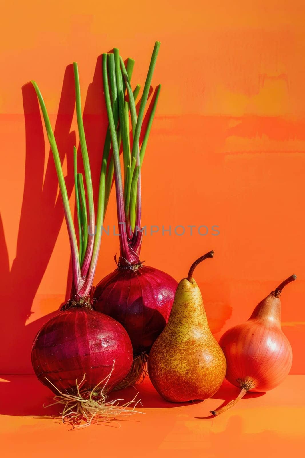 Group of red onions and pears on orange surface next to orange wall in kitchen setting by Vichizh