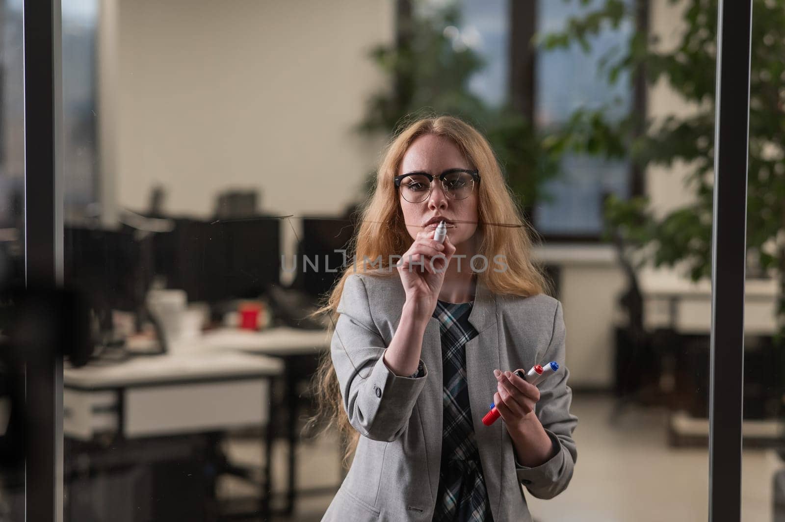 Caucasian woman writing pyramid diagram with questions on glass wall