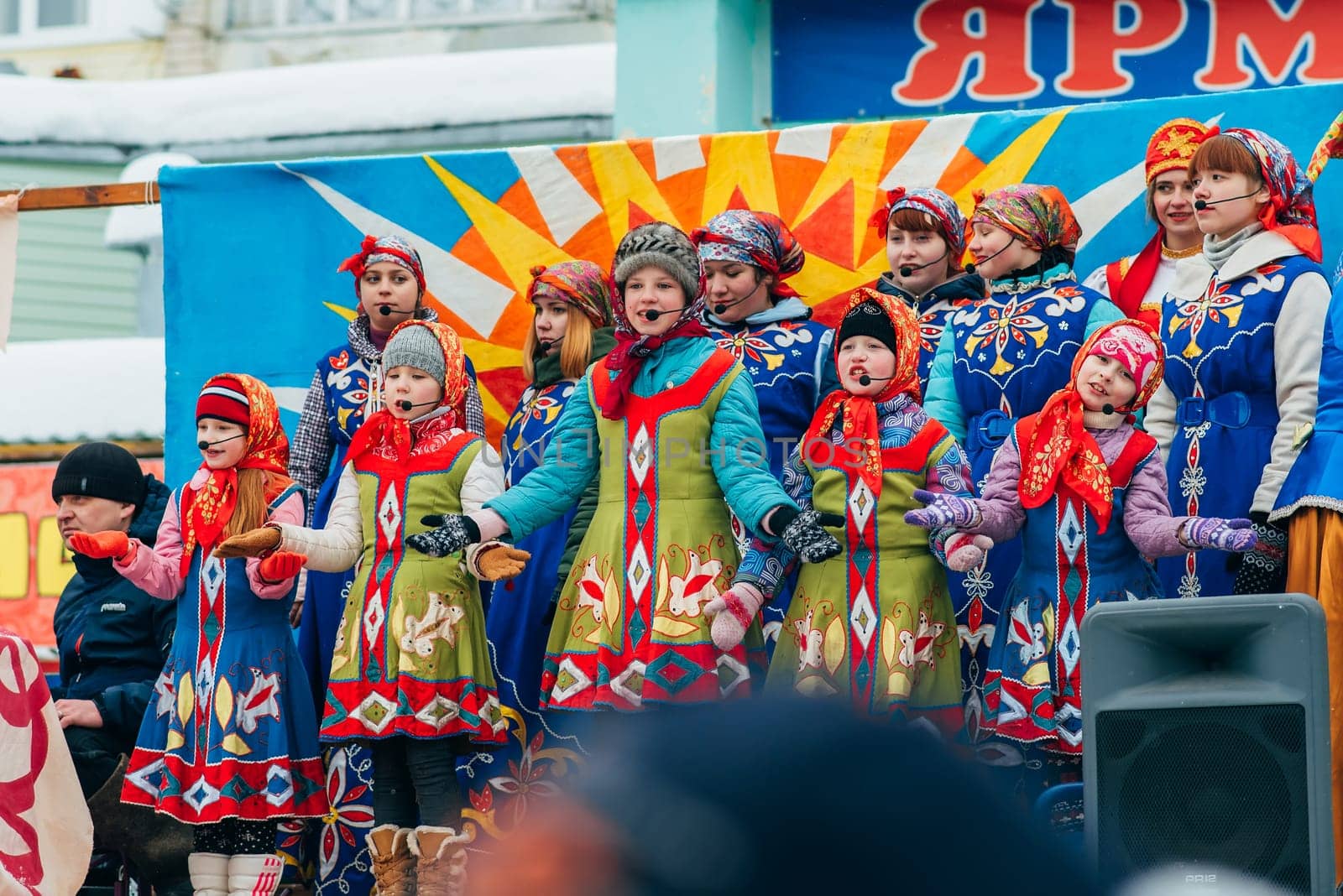 VICHUGA, RUSSIA - FEBRUARY 17, 2018: crowd of girls on stage sing songs in traditional Slavic costumes at the winter Russian celebration of the Maslenitsa holiday