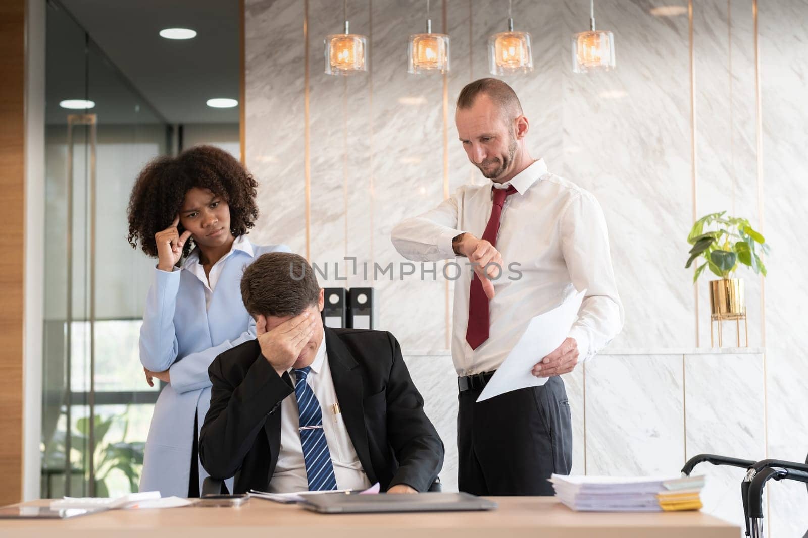 Frustrated diverse business team of three people, including a woman and two men, dealing with paperwork at an office desk, showing stress and disappointment, modern office setting