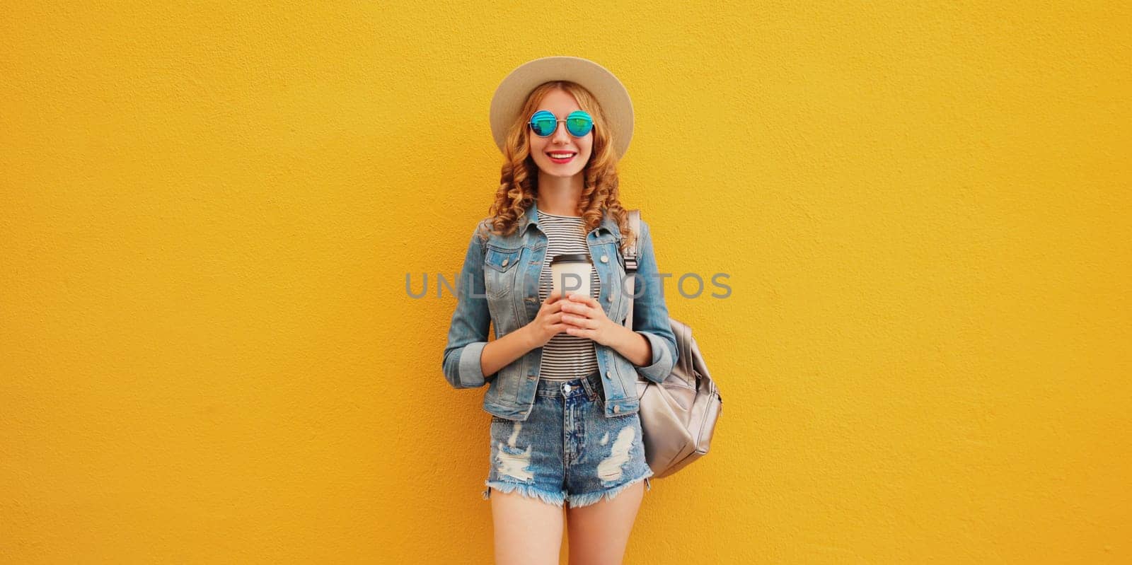 Summer stylish happy young woman with cup of coffee wearing summer hat on yellow background by Rohappy