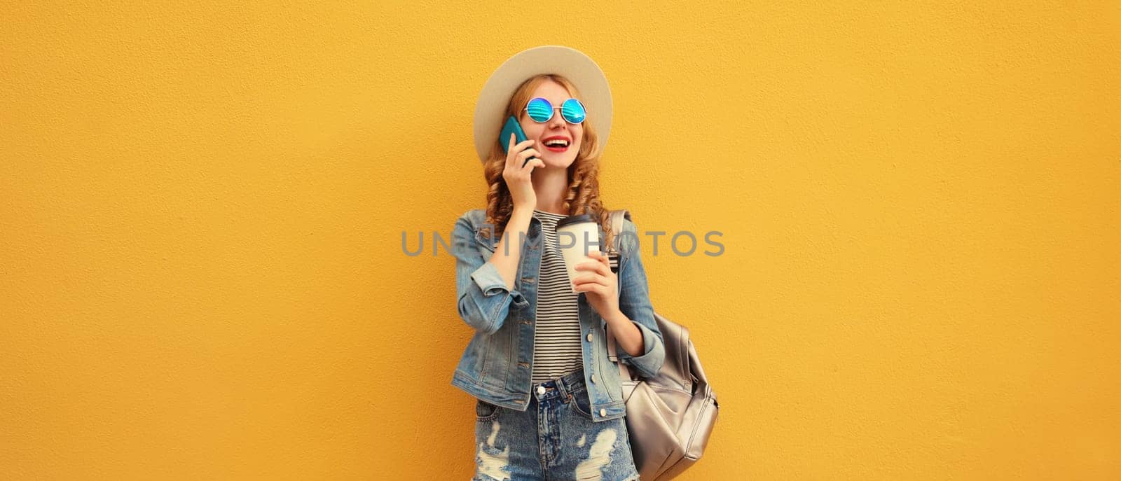 Summer happy cheerful young woman laughs calling on phone with cup of coffee looking away in straw hat on yellow background