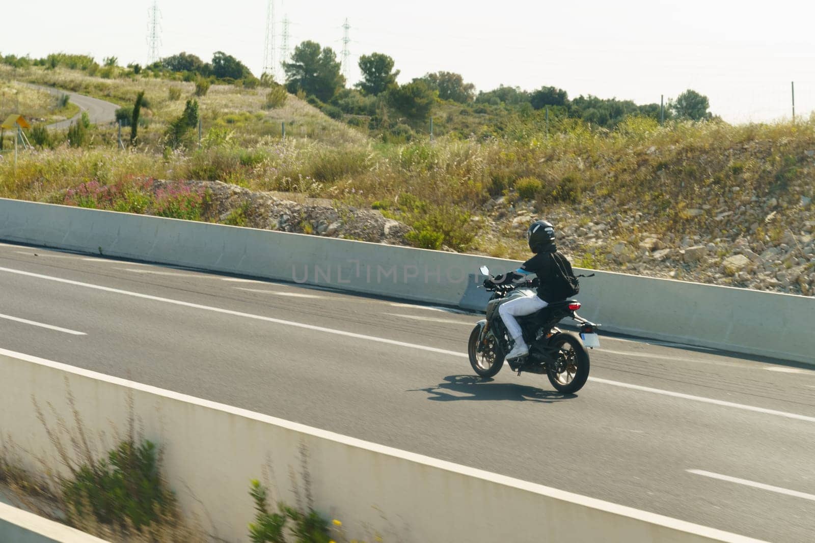 Salles-d'Aude, France - May 16, 2023: A person is riding a motorcycle on a highway, moving swiftly between lanes with traffic in the background.