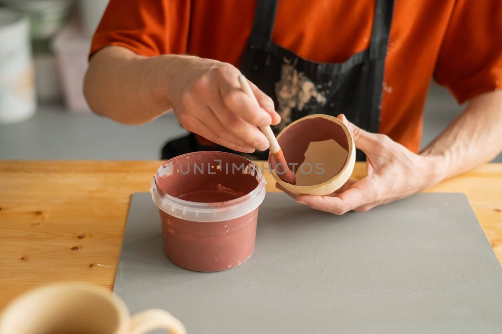 Close-up of a potter's hands with a brush painting ceramic dishes. by mrwed54