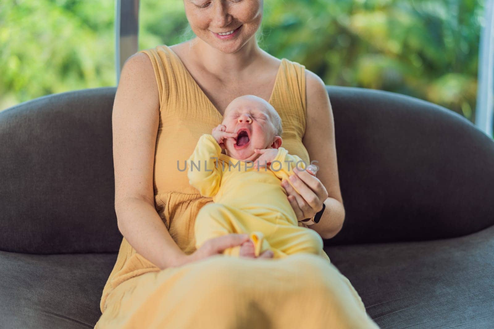 Mom with newborn baby relaxing on the sofa at home. This tender moment highlights the bond between mother and child in a comfortable and loving family environment.