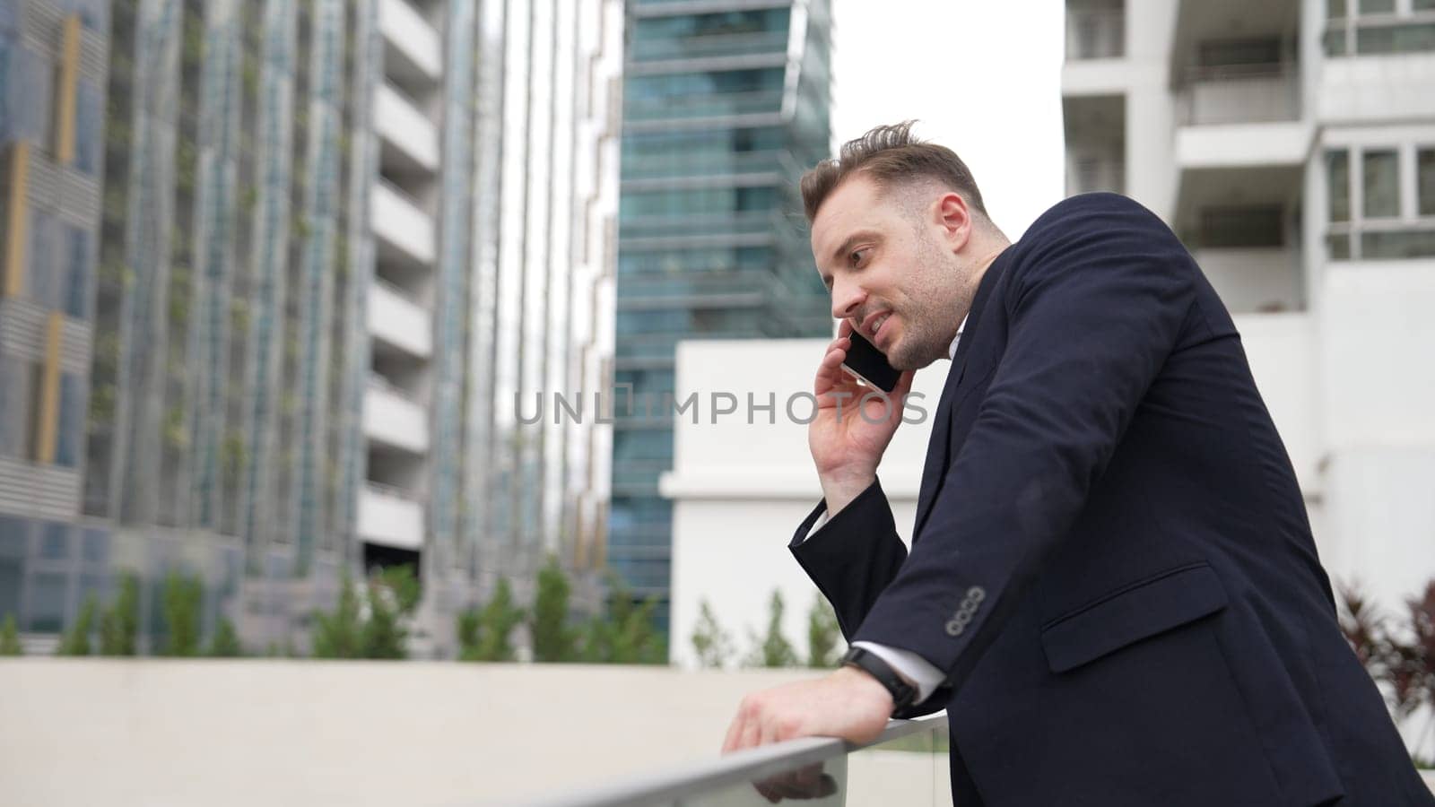 Smart caucasian businessman calling his colleague to plan financial strategy while standing at rooftop. Project manager using his mobile phone to communicate with marketing team. Lifestyle. Urbane.