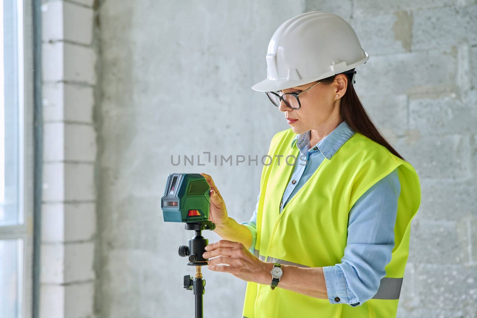 Woman industrial worker builder engineer in protective vest helmet working on construction site with professional equipment. Construction industry technical professions work engineering