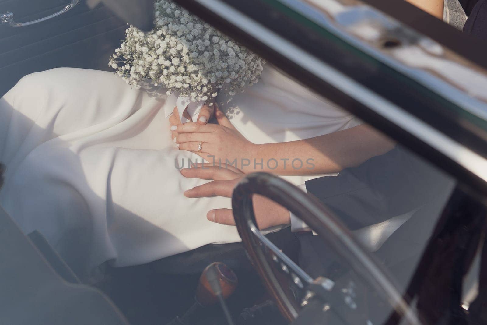 Bride with bouquet and ring in vintage car. Groom is driving cadillac