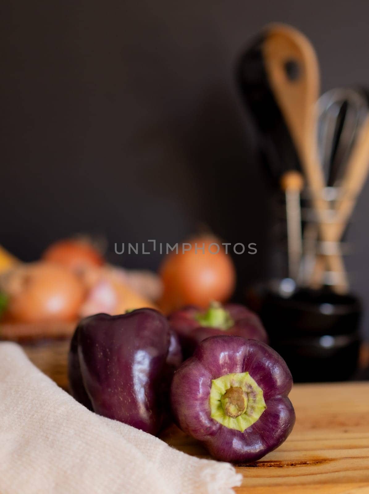 Dark purple pepperof on rustic wooden table.Black background. by VeroDibe