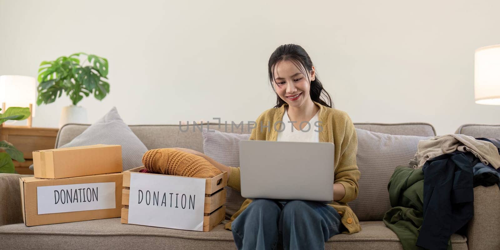 A young woman volunteers to donate clothes, sorting items into donation boxes, showcasing community service, charity, and generosity.