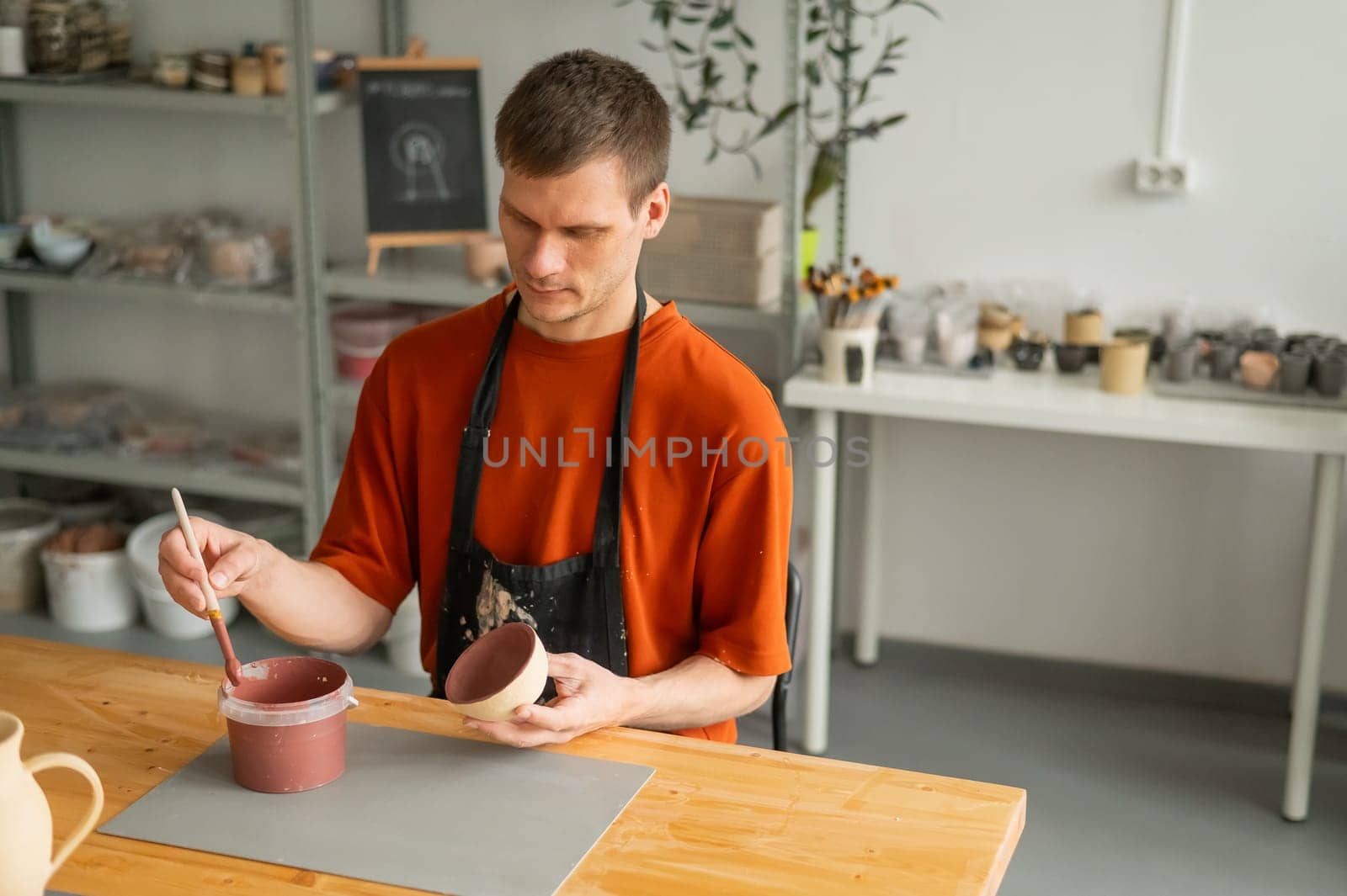 Potter paints ceramic dishes with a brush