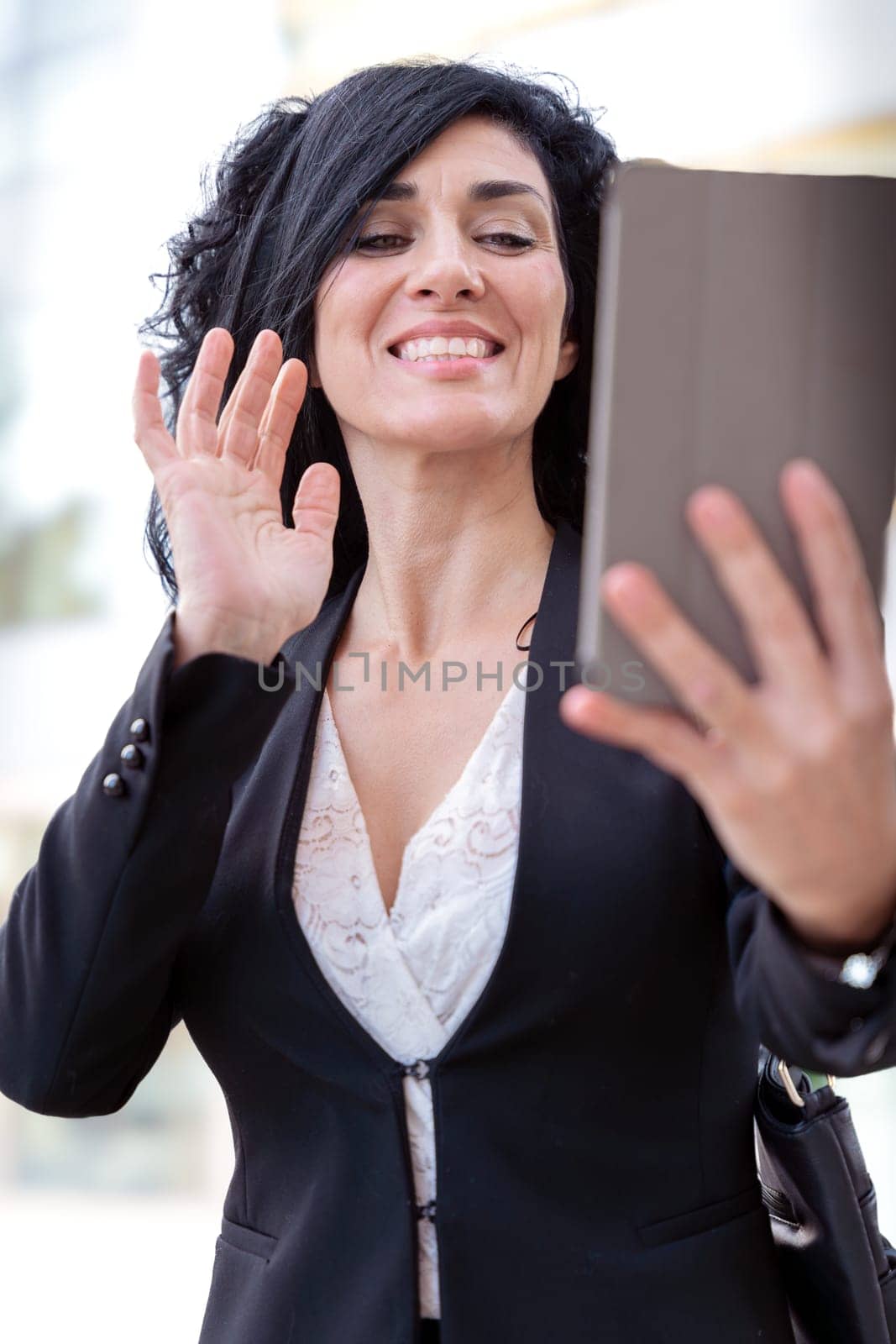 Vertical portrait of smiling caucasian businesswoman on a video call with tablet by mariaphoto3