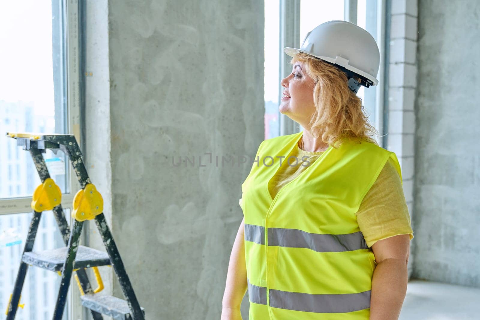 Technical profession woman in protective vest helmet working on construction. Confident serious industrial female engineer builder inspector supervisor architect with papers. Construction industry