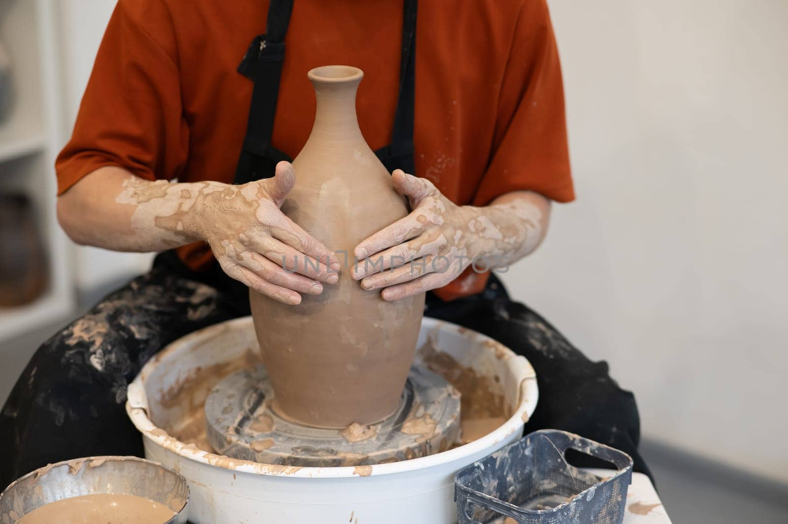 Close-up of a potter's hands making a ceramic vase on a potter's wheel