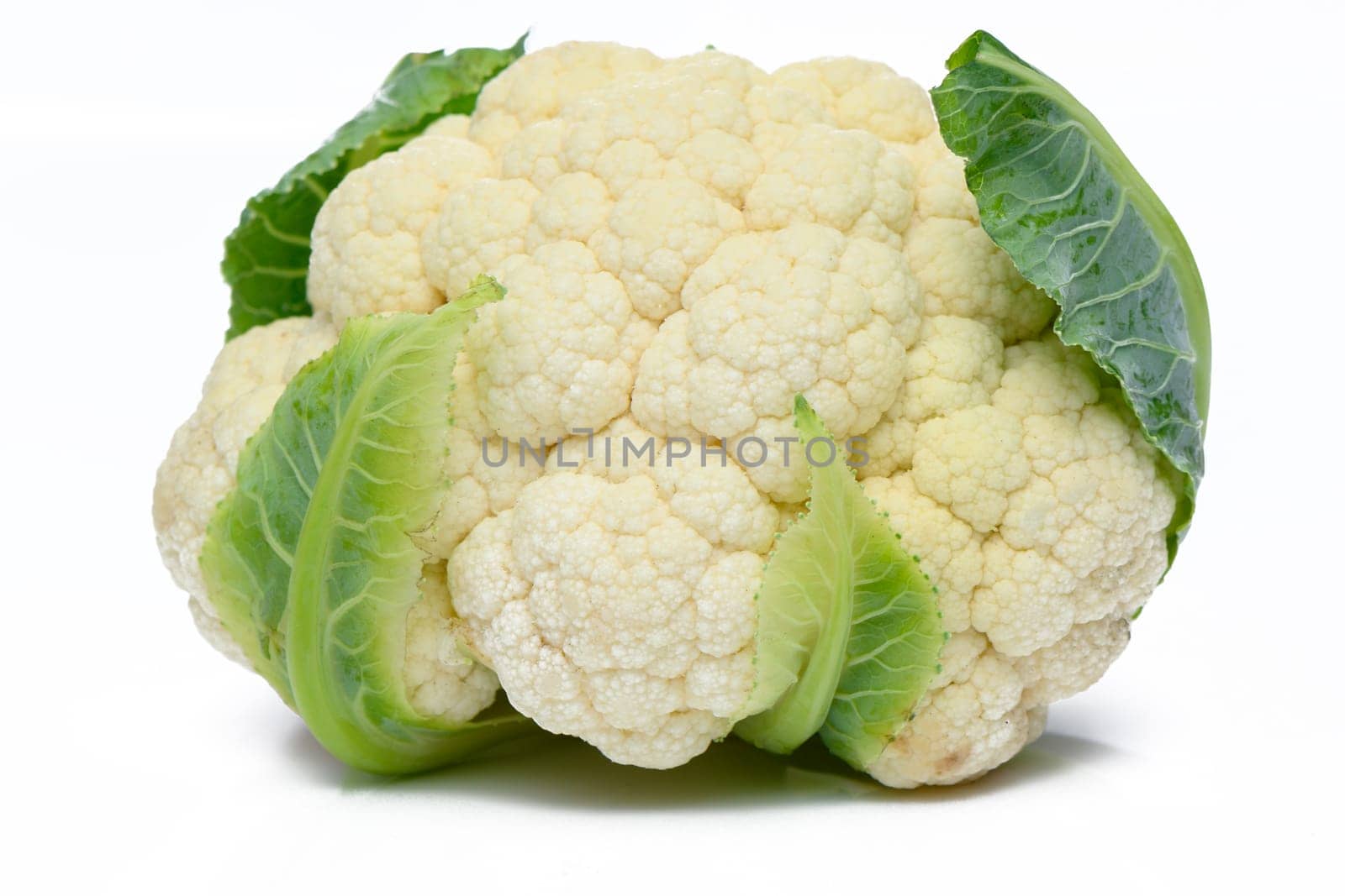 Whole head of the fresh raw cauliflower with some leaves close-up on a white background by Mixa74