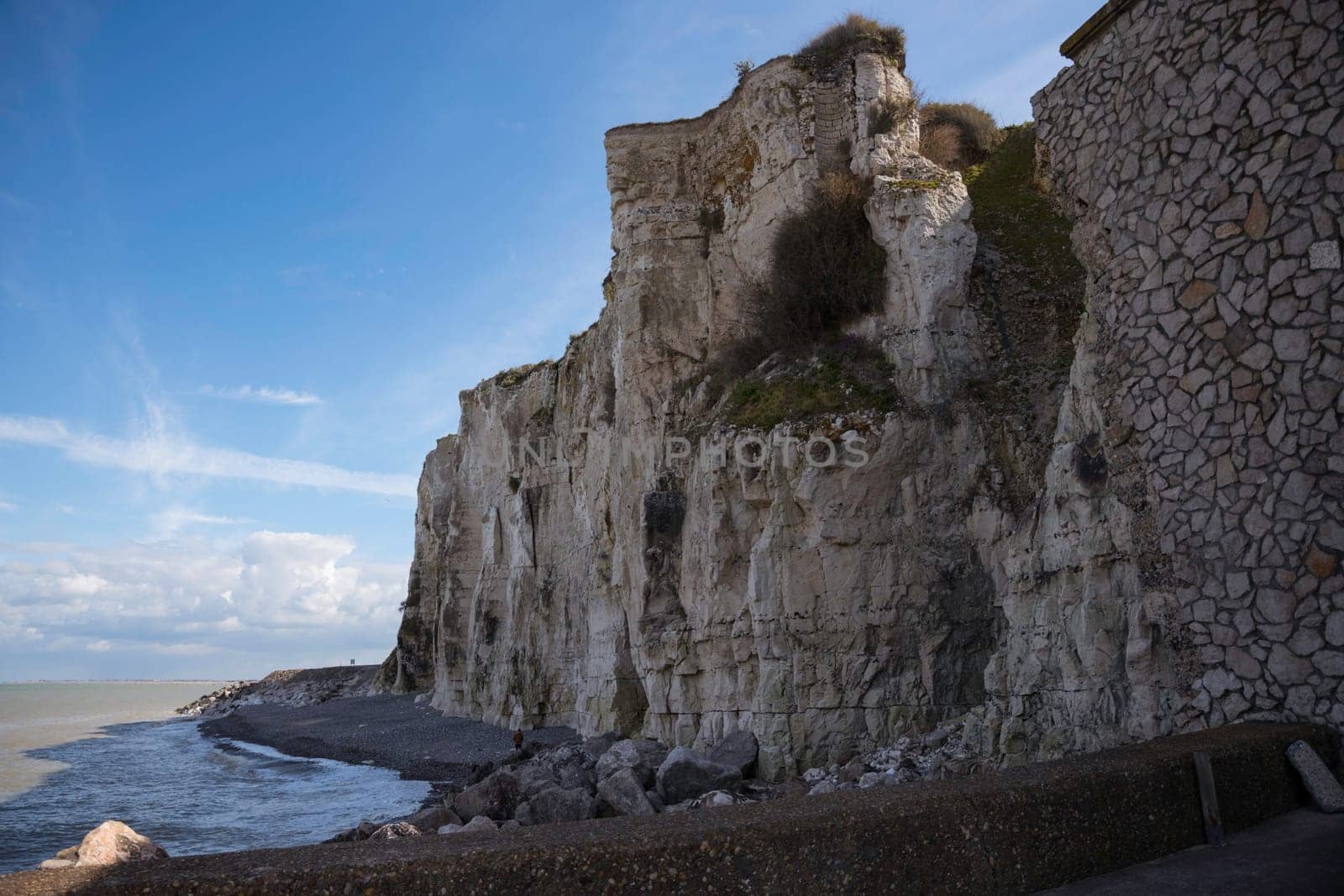 the chalk cliffs of etretat in France in Normandy with a blue sky with white clouds and the sea
