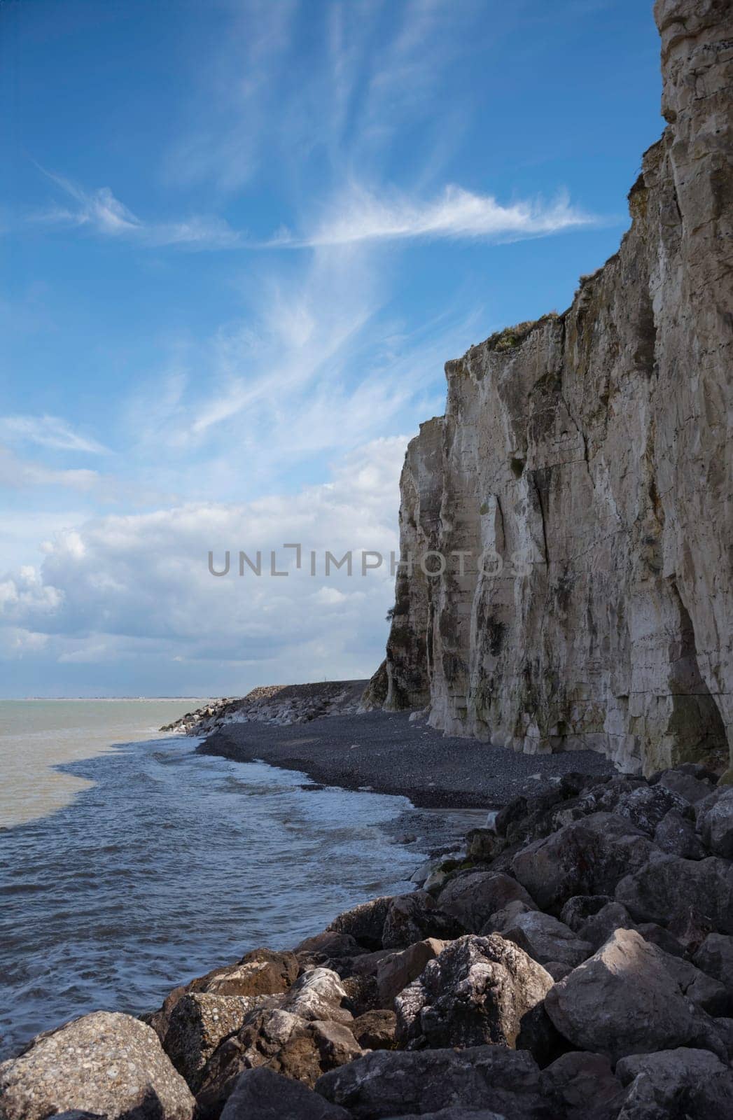 the chalk cliffs of etretat in France in Normandy with a blue sky with white clouds and the sea