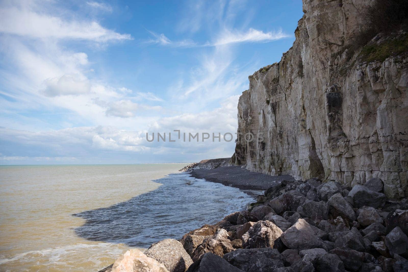 the chalk cliffs of etretat in France in Normandy with a blue sky with white clouds and the sea