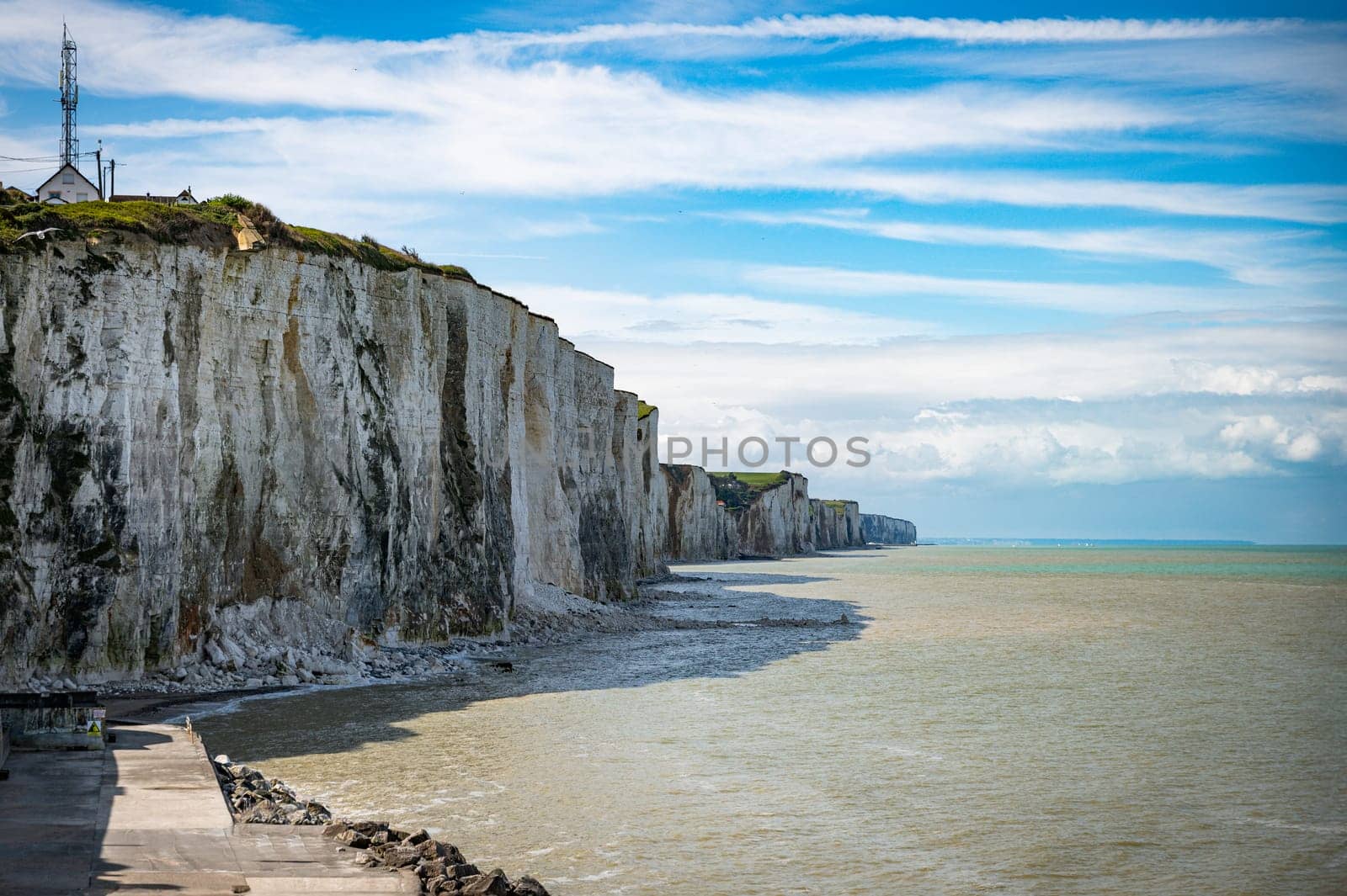 the chalk cliffs of etretat in France in Normandy with a blue sky with white clouds and the sea