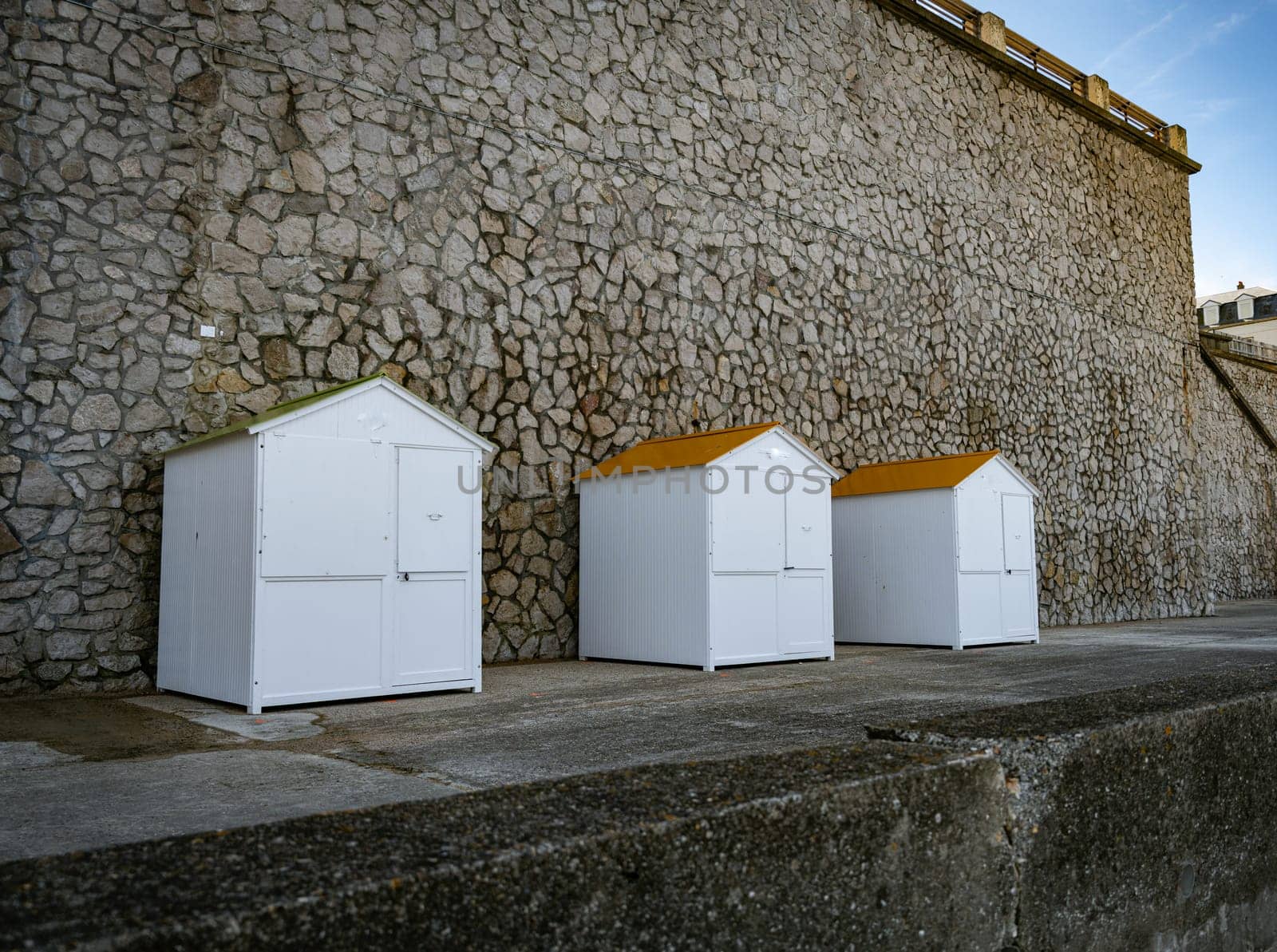 three white wooden beachhouses on the coastline of etretat in normandy in france with walls from rocks