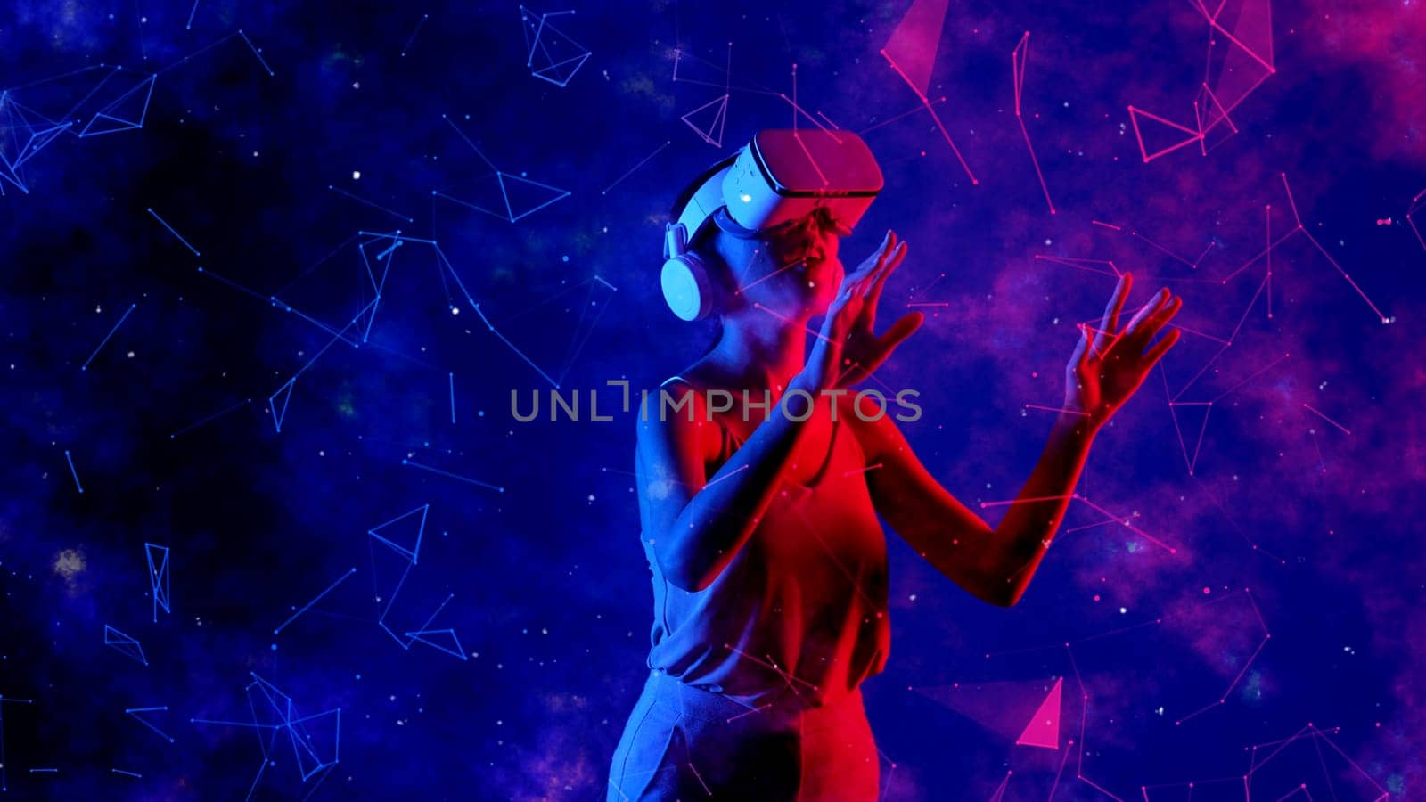 Excited smiling Asian woman looking around through VR metaverse with pointing on blue neon digital universe starry zodiac virtual space fantastic exploration nebula vibrant meta world. Hallucination.