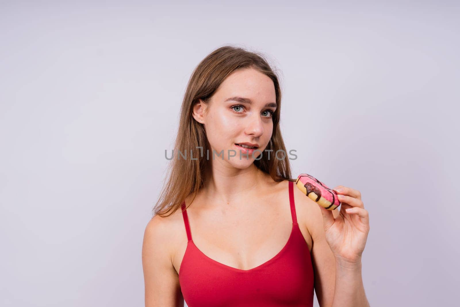 Lovely young caucasian woman in a sports wear with donuts on grey and yellow studio background.