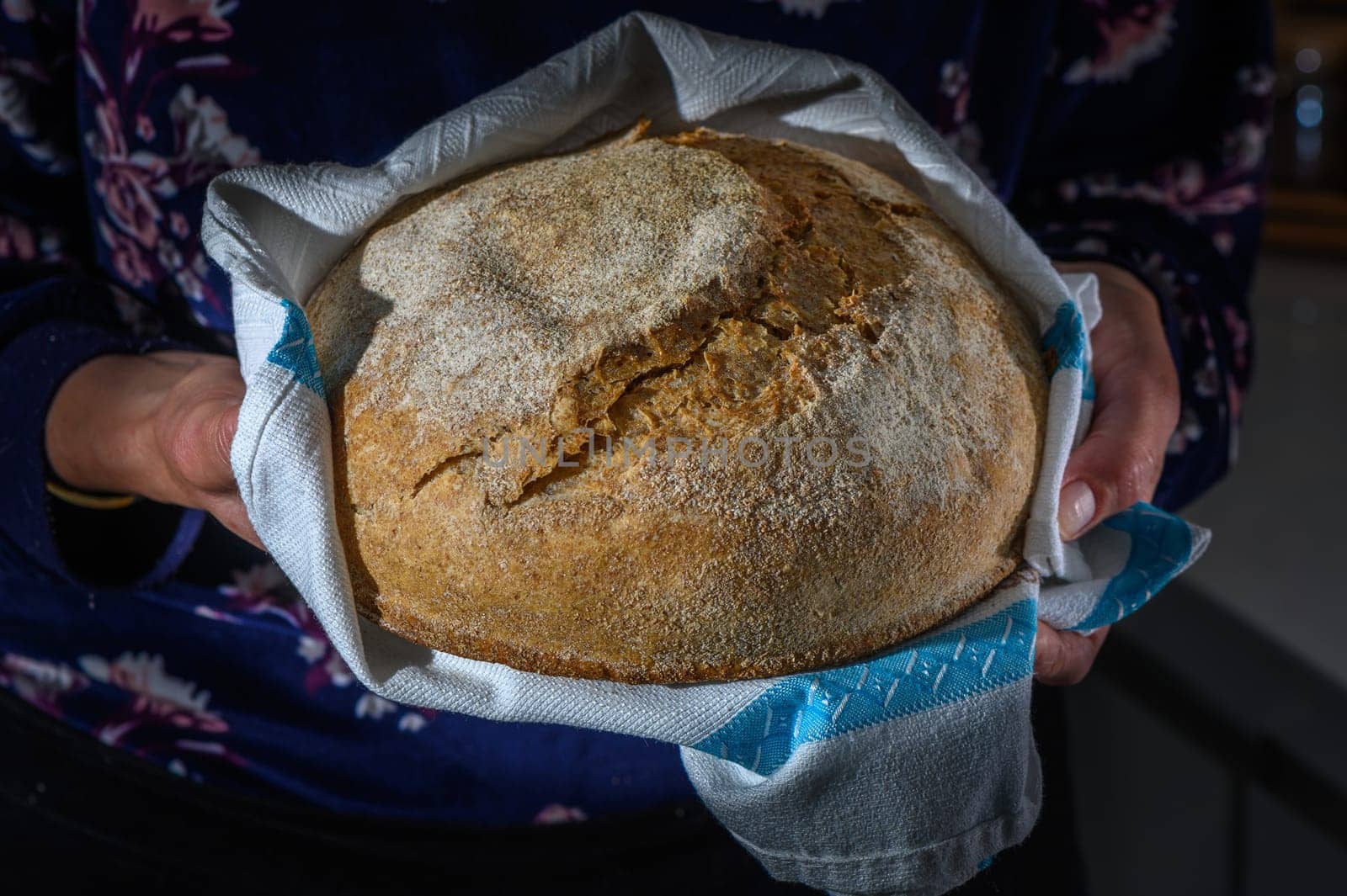 Traditional leavened sourdough bread in baker hands on a rustic . Healthy food photography by Mixa74