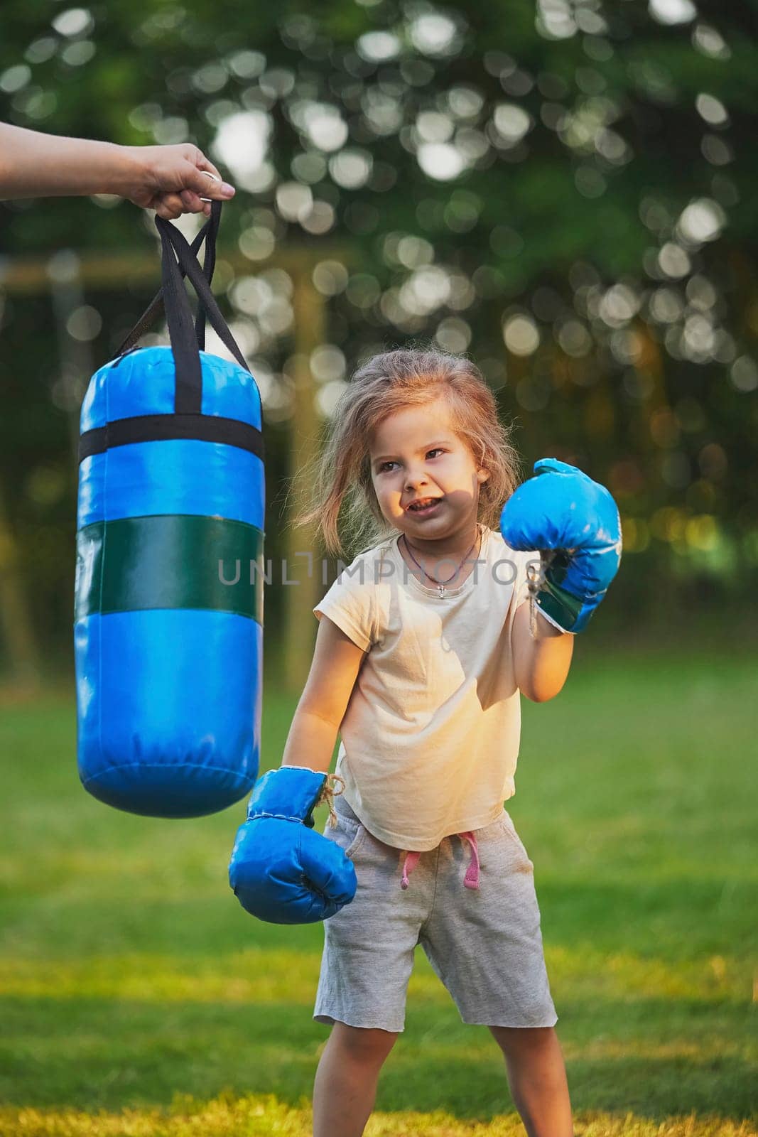 Charming child doing boxing in the backyard on the Sunset.