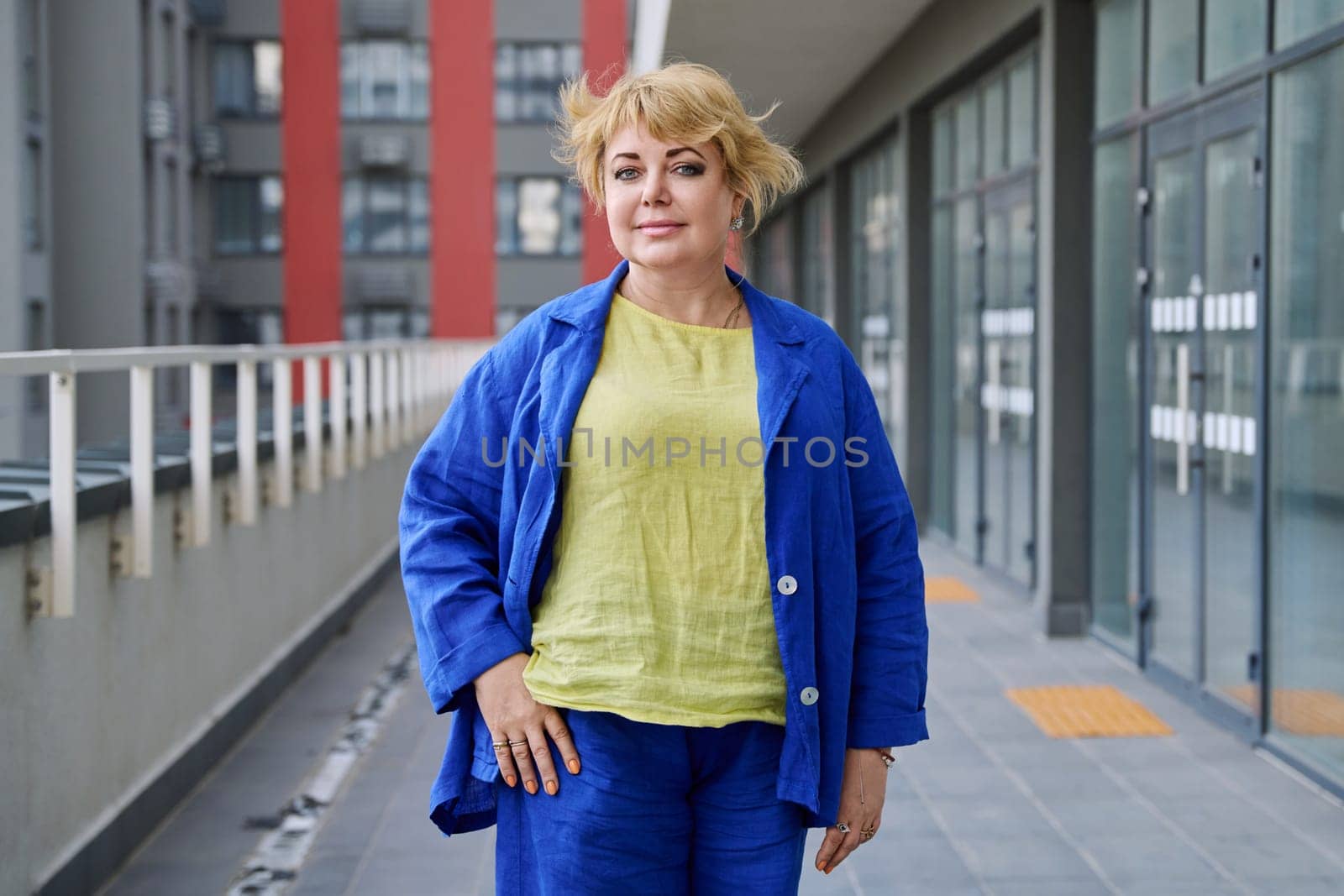 Portrait happy elegant mature woman 50 years old outdoor, urban background. Smiling beautiful blonde female looking at camera in city. Age, lifestyle, beauty, fashion concept