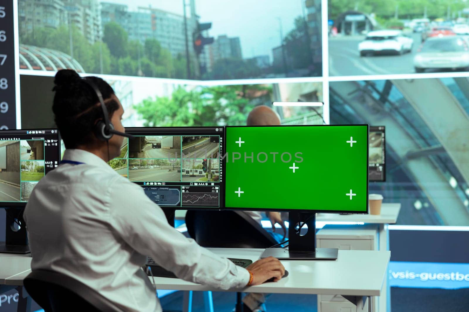 Indian specialist monitoring traffic surveillance next to a greenscreen display, gather intelligence on traffic activity in the city. Government employee collecting data on cars, plate recognition.