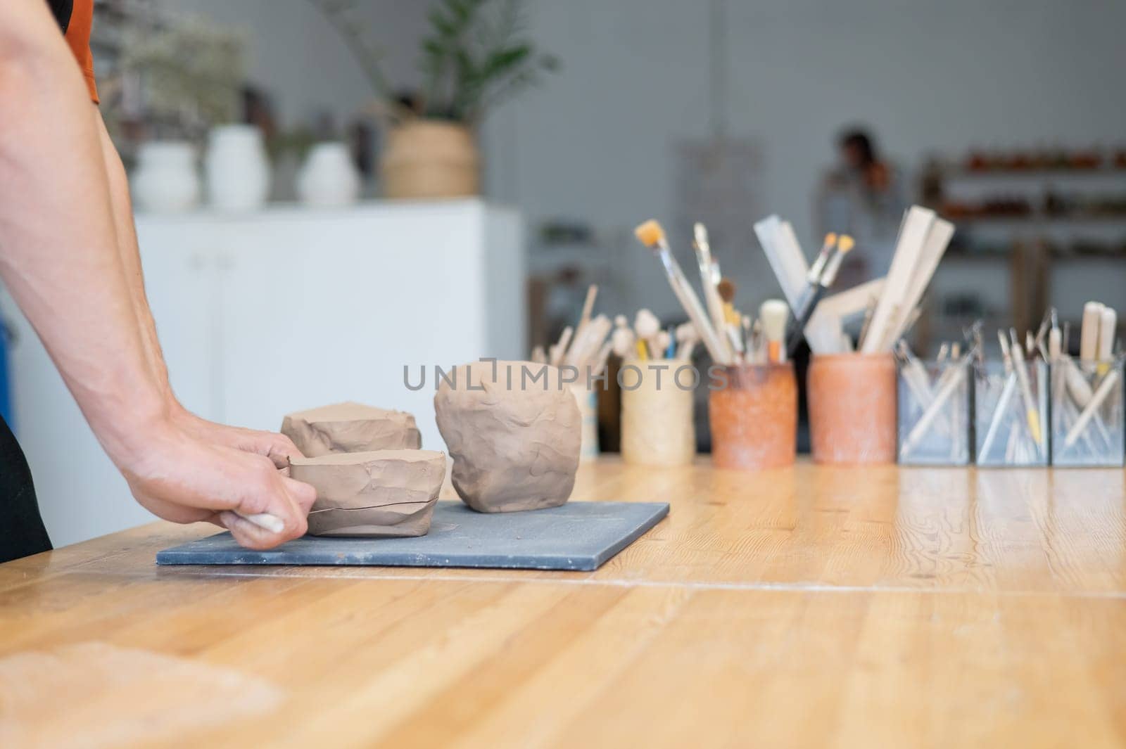 A potter cuts a piece of clay into pieces before using it in the workshop. by mrwed54