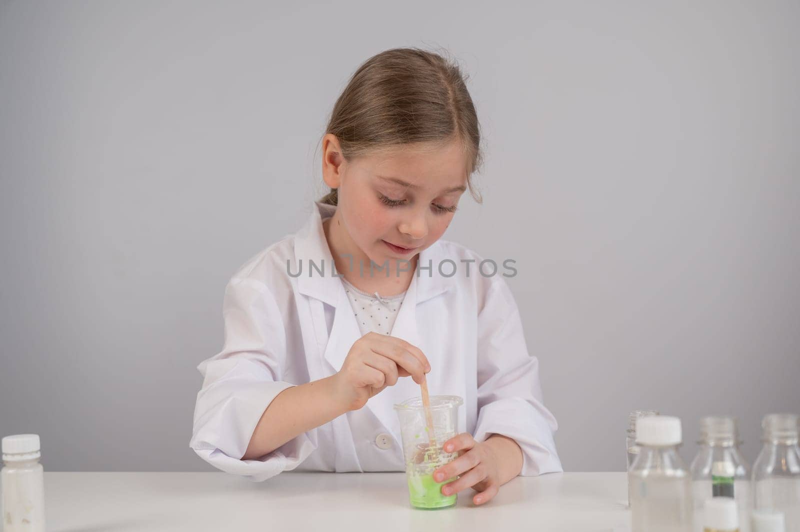 Caucasian girl doing chemical experiments on a white background. Making slime