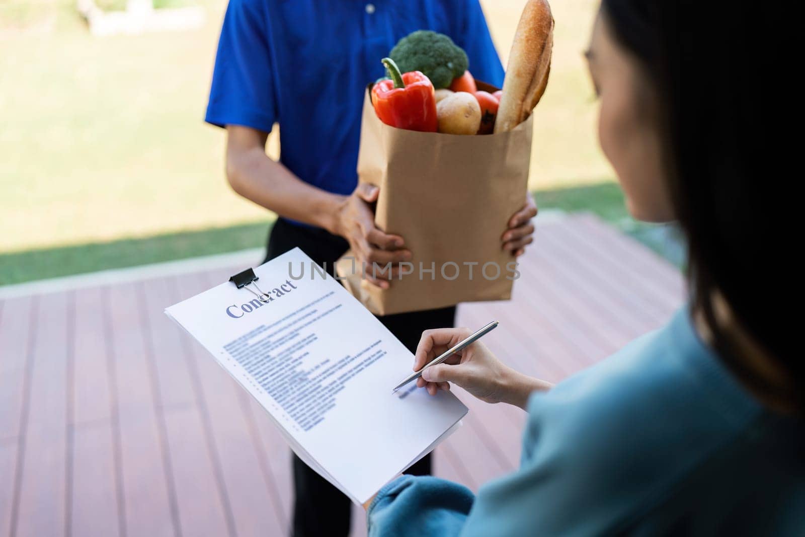 Home Delivery Service Customer Receiving Grocery Package and Signing for Delivery Confirmation by itchaznong