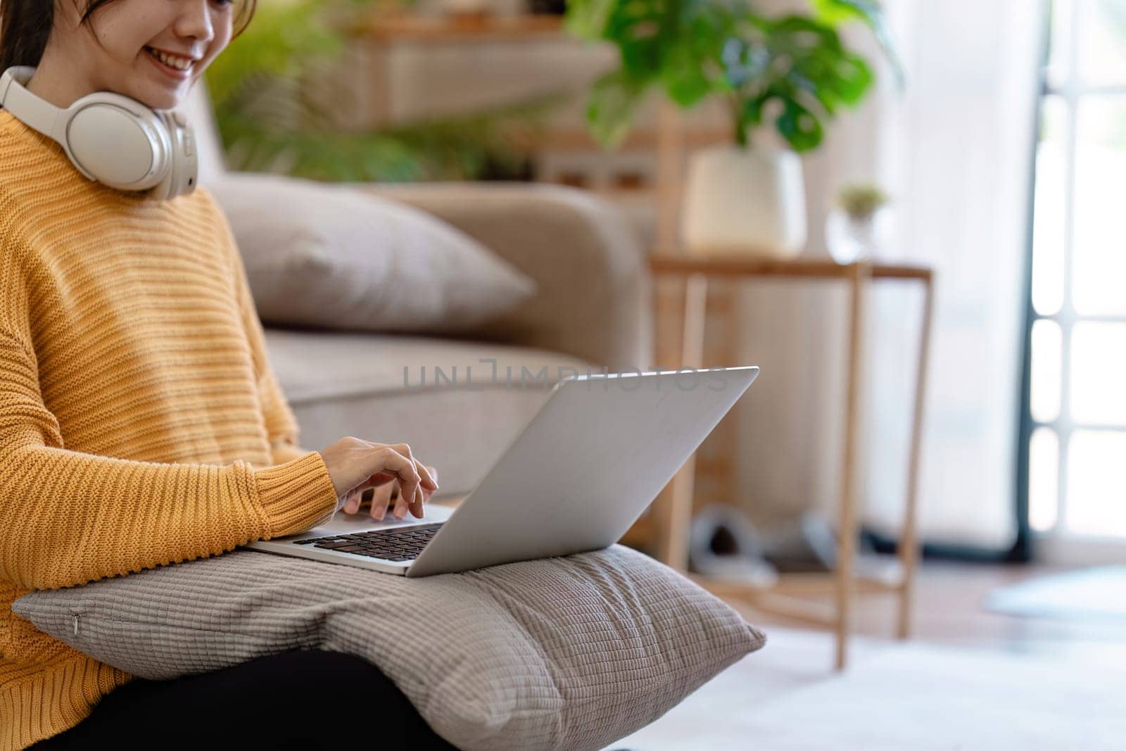 Young Woman Enjoying Modern Lifestyle at Home with Laptop and Headphones in Cozy Living Room Setting by itchaznong